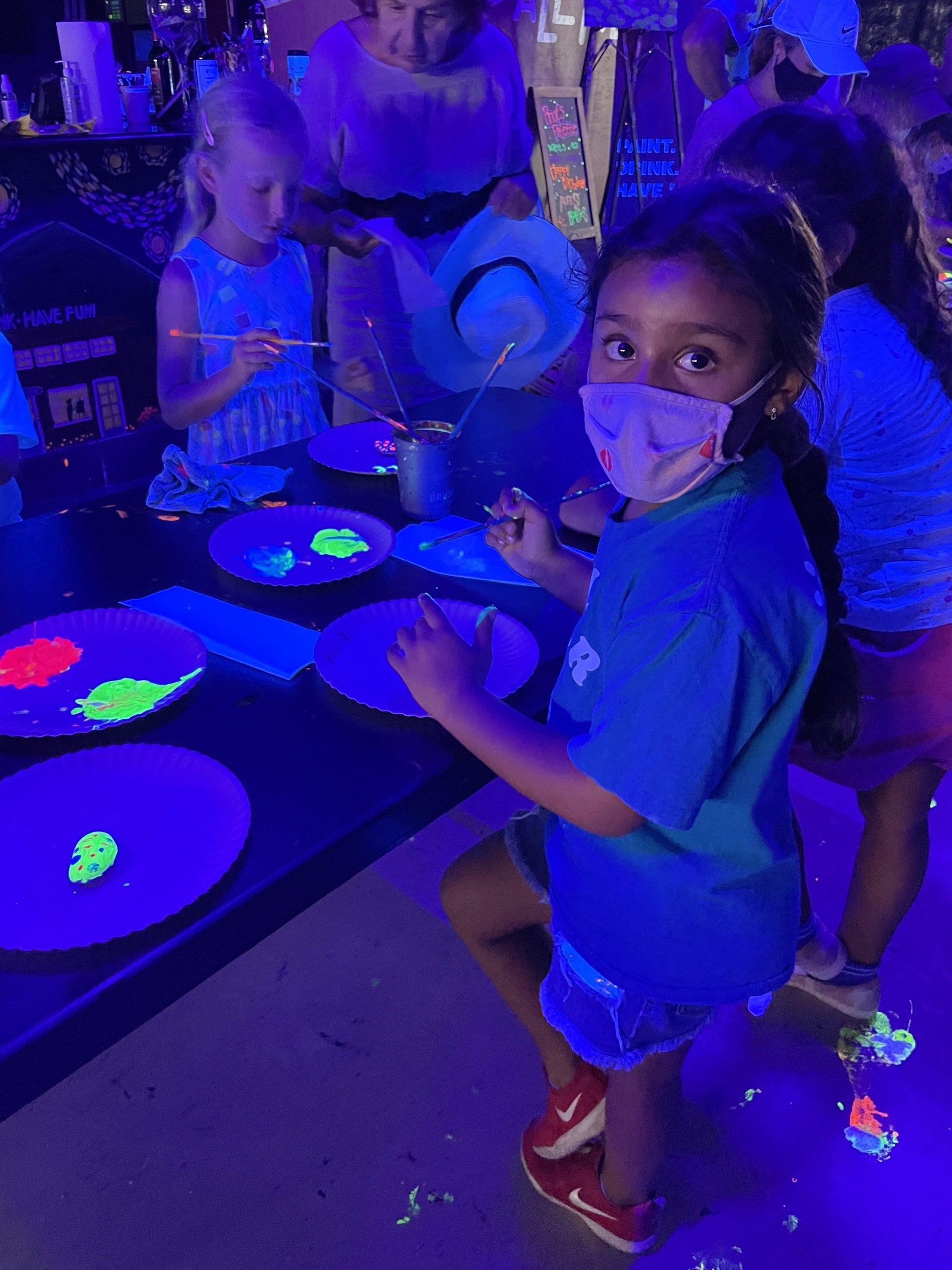 A group of children are playing with glow in the dark paint.
