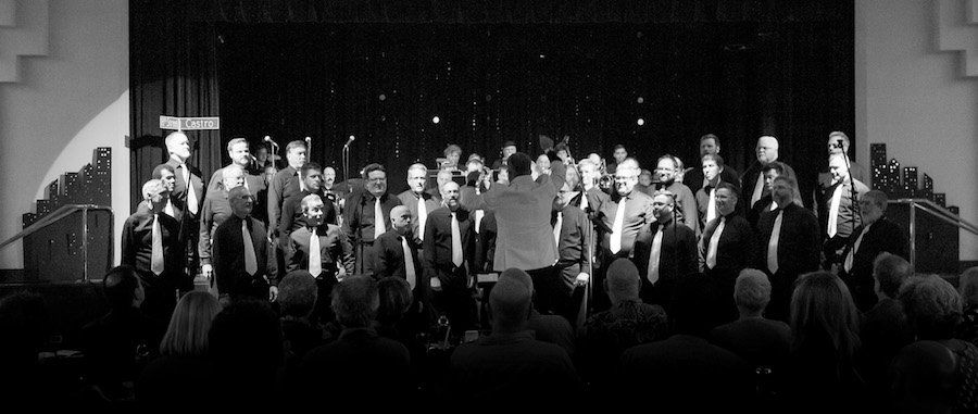 A black and white photo of a group of people standing on a stage.