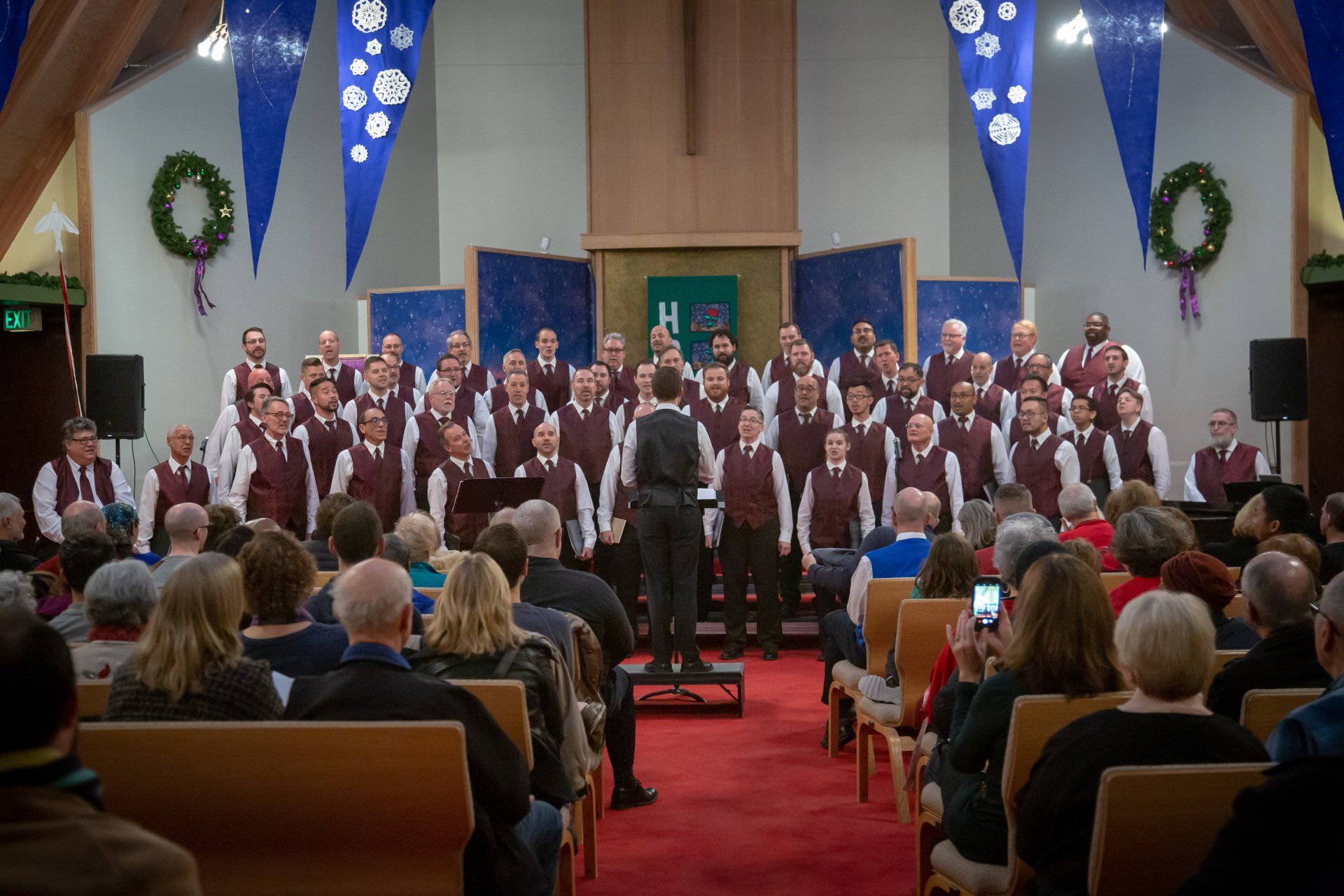 A choir is performing in front of a crowd of people in a church.