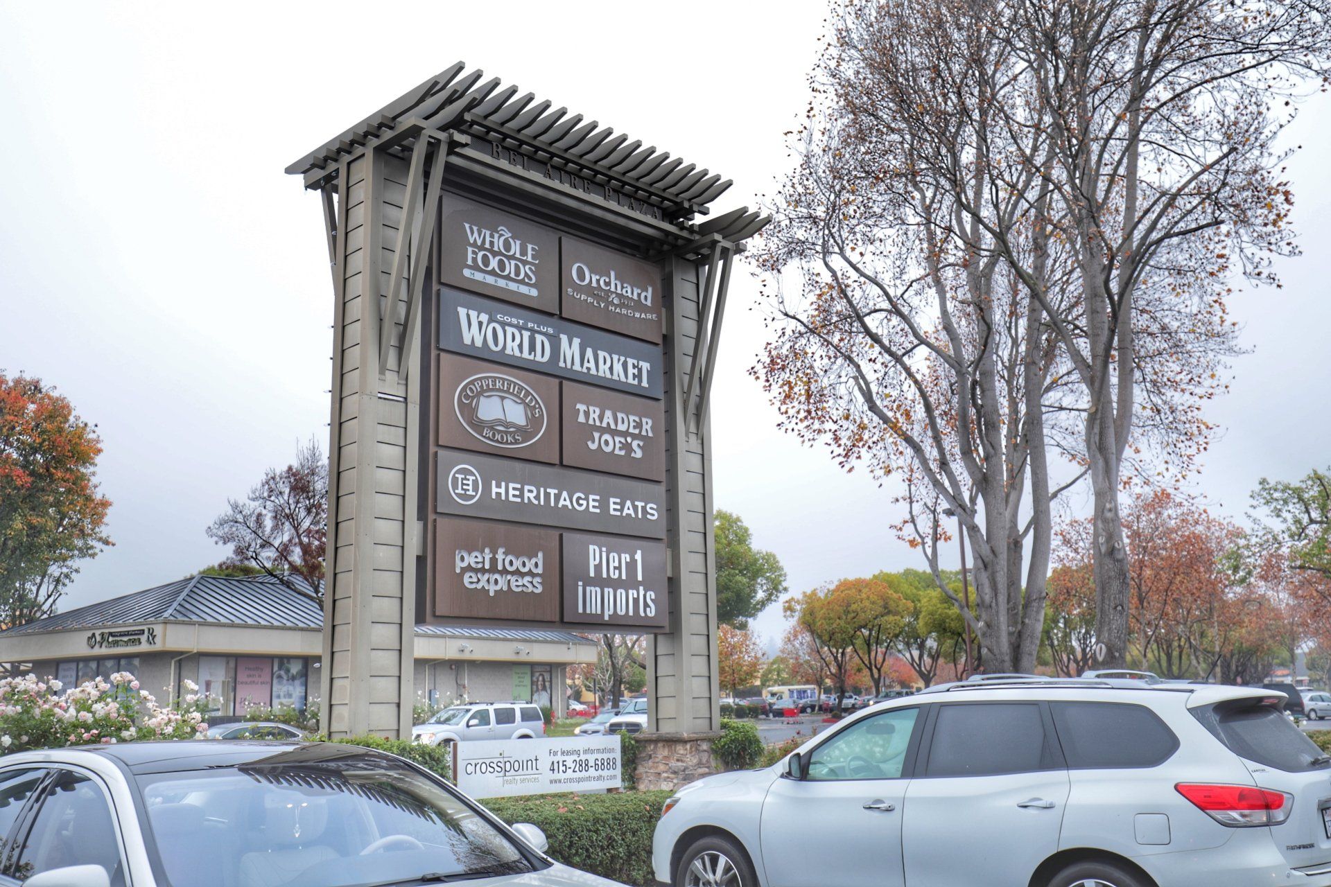 A group of cars are parked in front of a large sign.