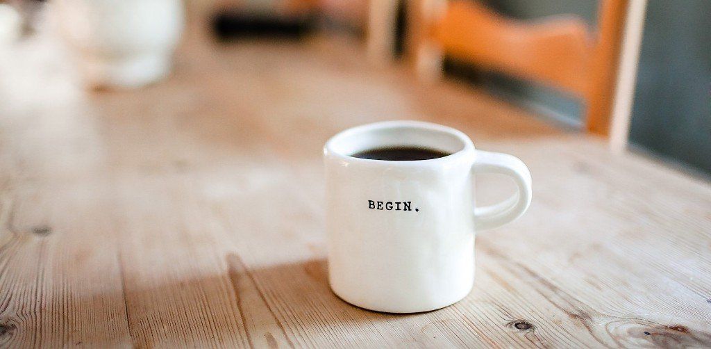 A cup of coffee is sitting on a wooden table.