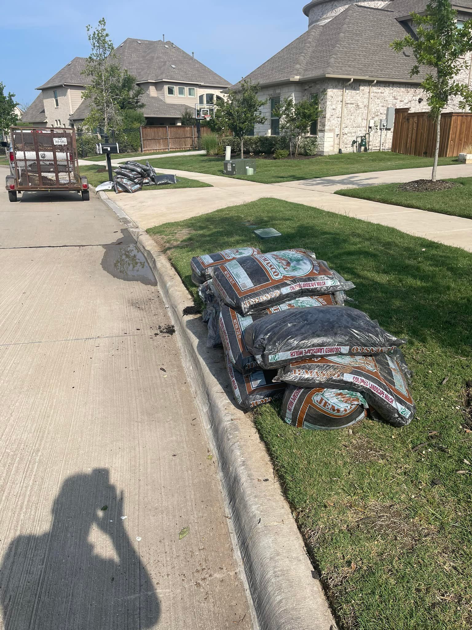 A stack of bags sitting on the side of a road next to a house.