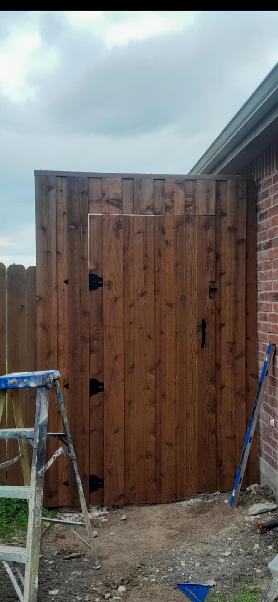 A wooden gate is being built next to a brick building.