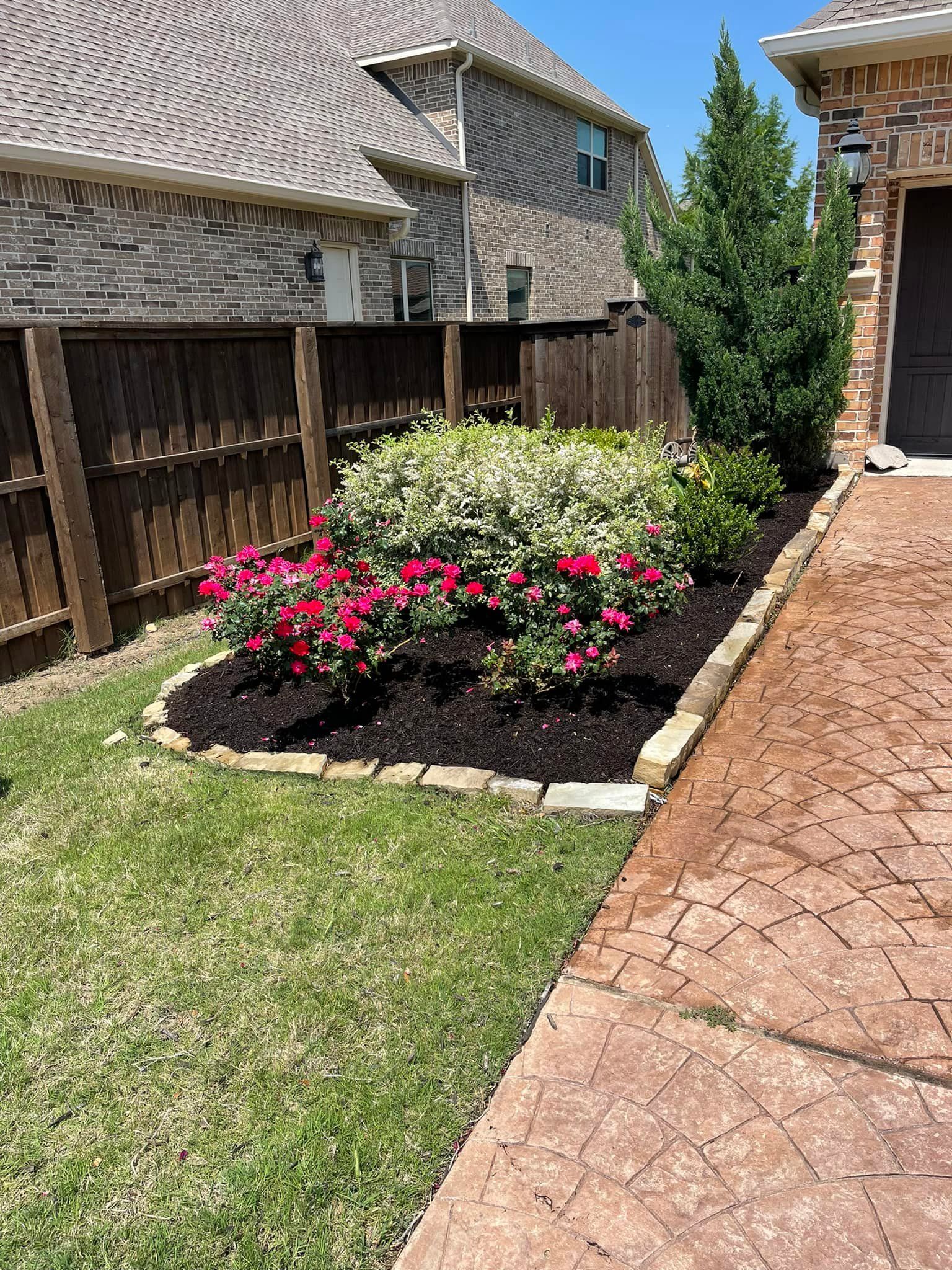 A garden with flowers and mulch in front of a house.
