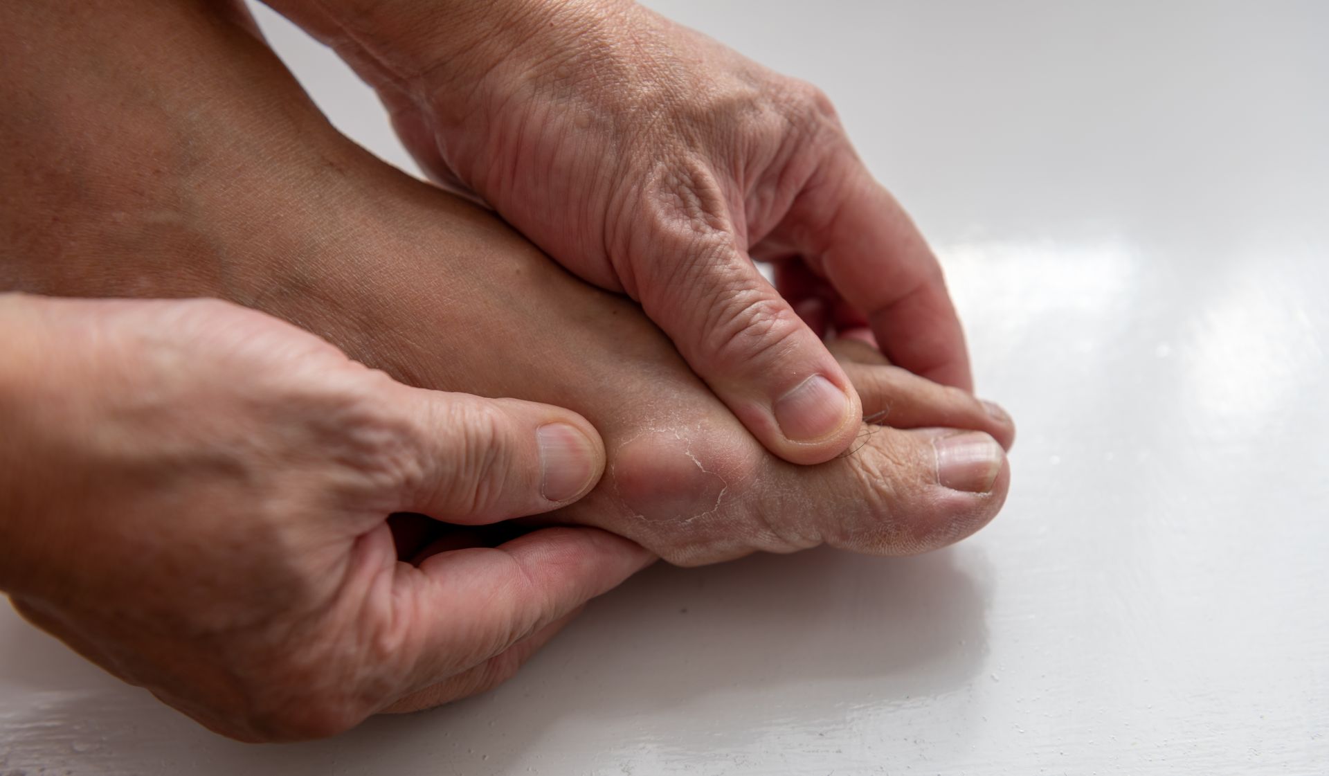 Hands holding and examining foot, possibly with pain or injury.