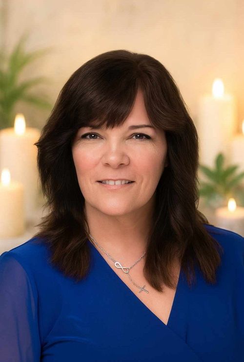 Barbara Barton in front of lit candles, wearing a blue top and a silver necklace.