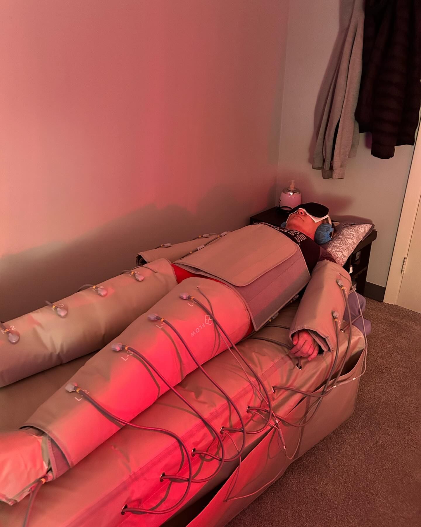 A person is laying on a bed with a red light behind them.