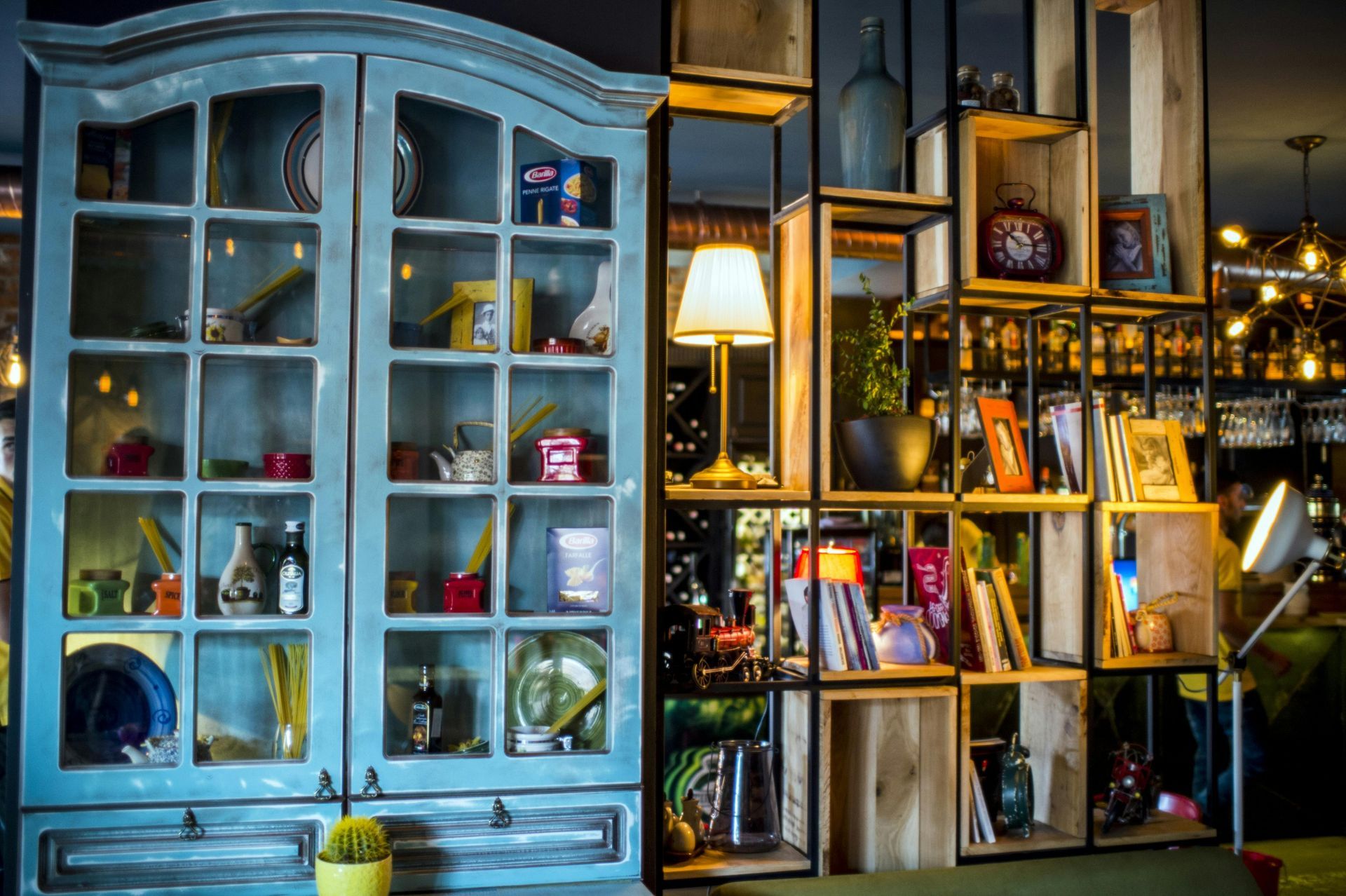 Blue cabinet and wooden shelves filled with decor in a cafe.