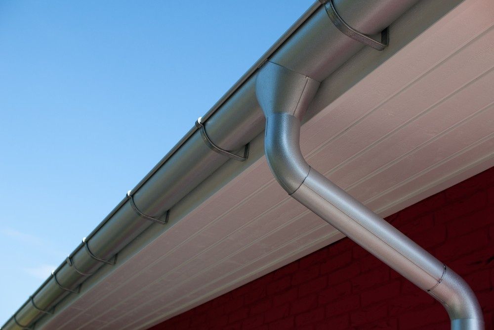 Silver Rain Gutter and Downspout Attached to a Red and White House — House Guttering in Eli Waters, QLD