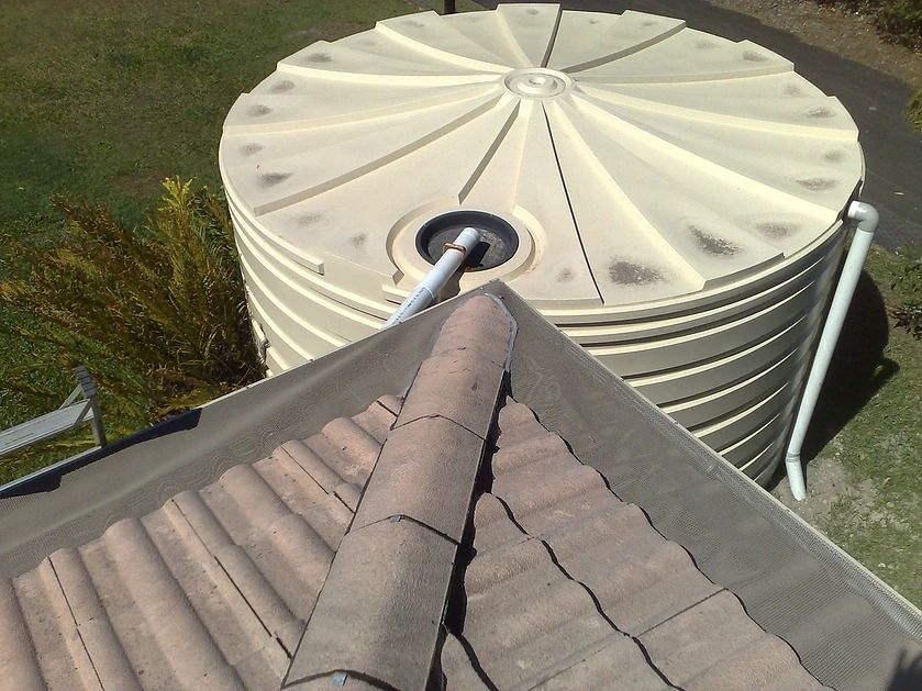 A Water Tank Is Sitting On Top Of A Tiled Roof — House Guttering in Bauple, QLD