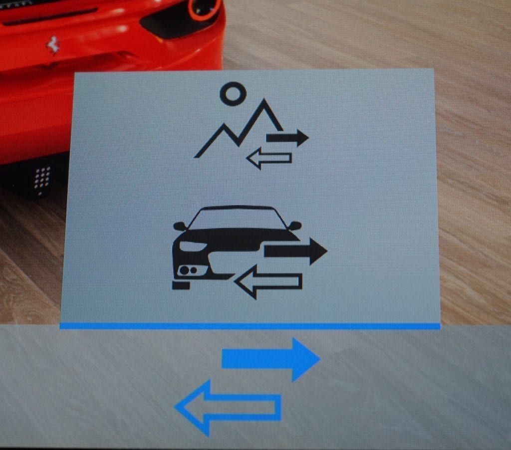 Dashboard display with two icons: a mountain and a car, each with bidirectional arrows, indicating navigation options.