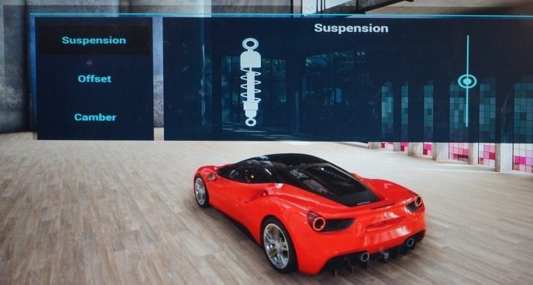 A red sports car in a garage with a suspension adjustment screen.