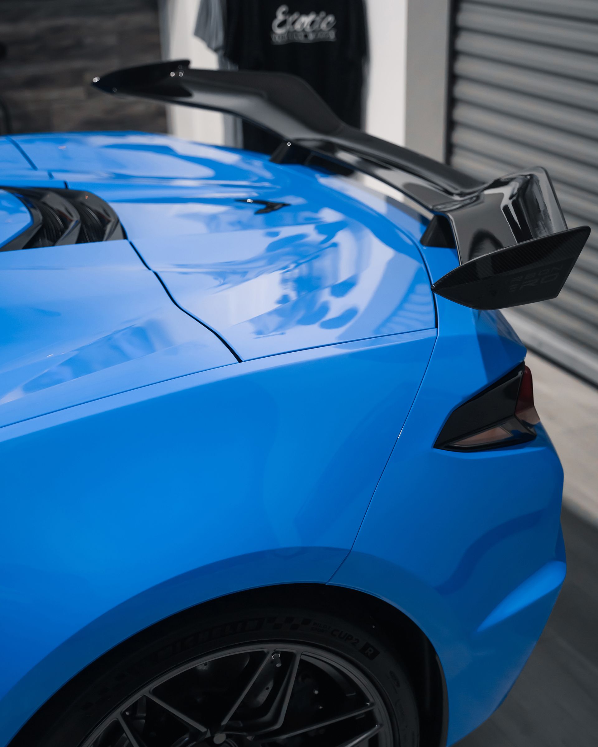 Blue sports car with black spoiler; outdoors.