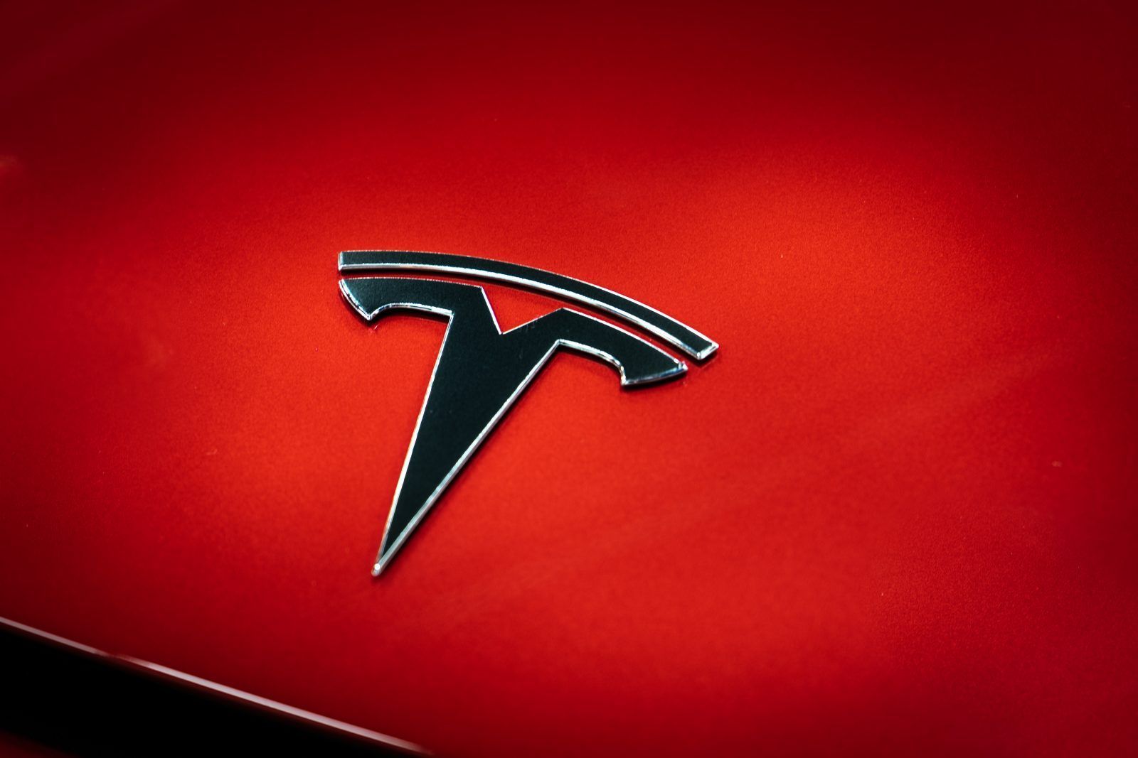 Black Tesla logo on a red car.
