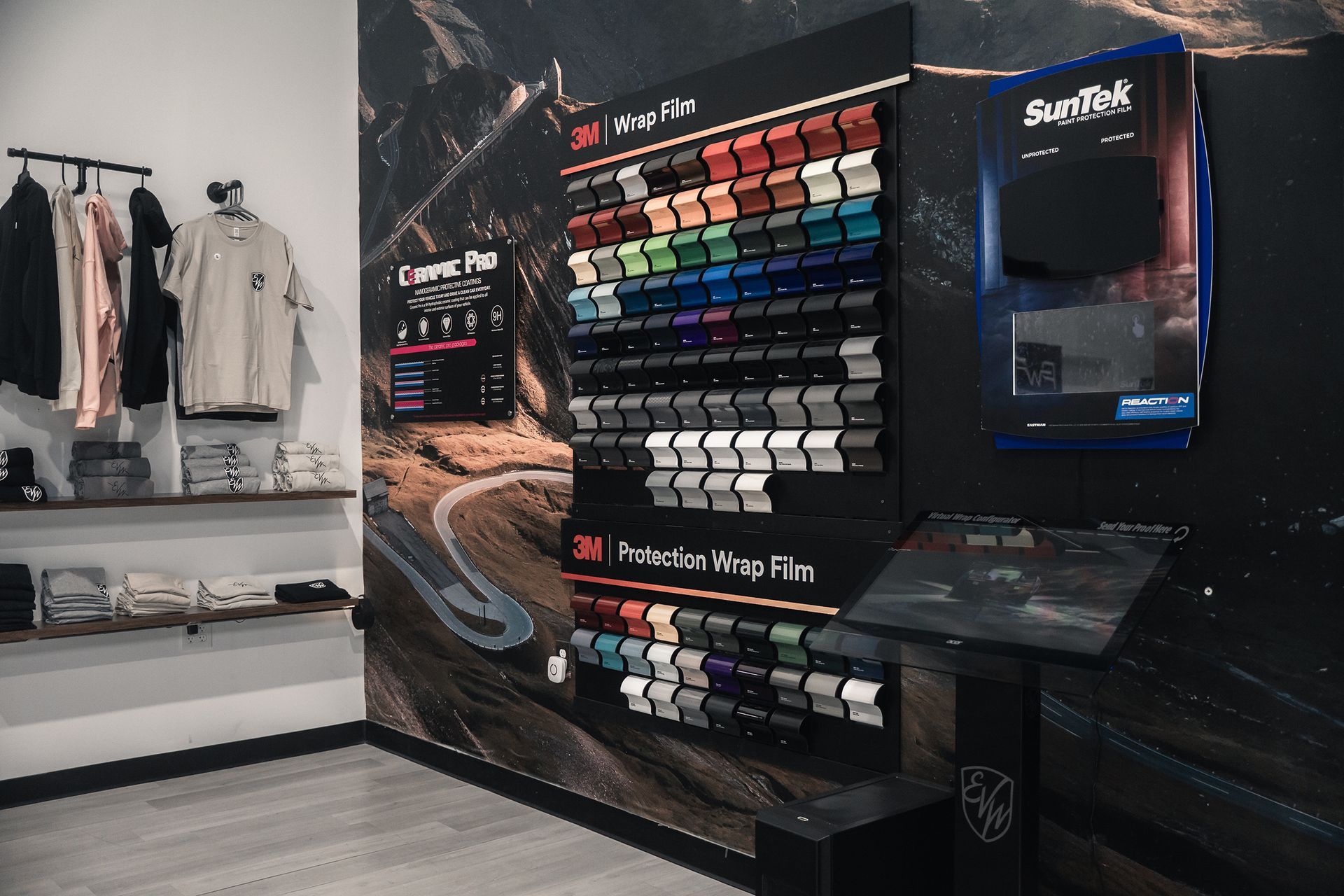 A showroom with a color palette display, clothing rack, and wall art featuring a winding road.