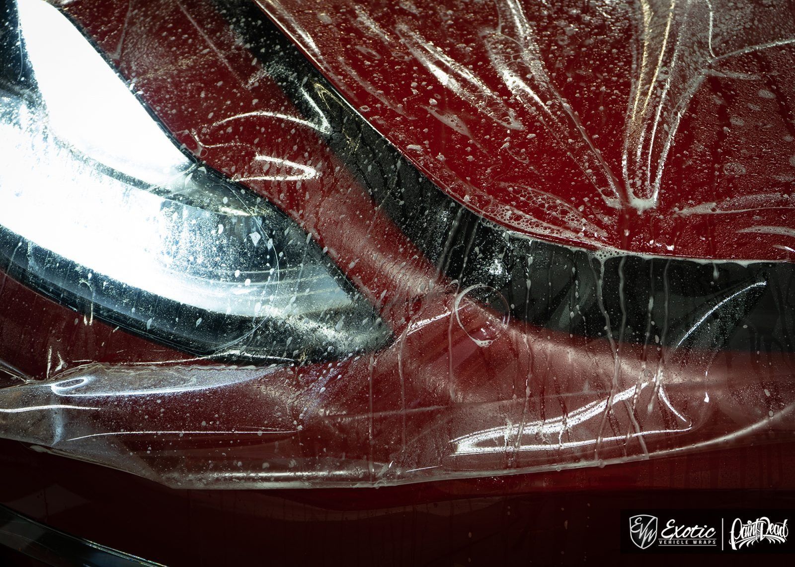 Red car with protective film applied, close-up.