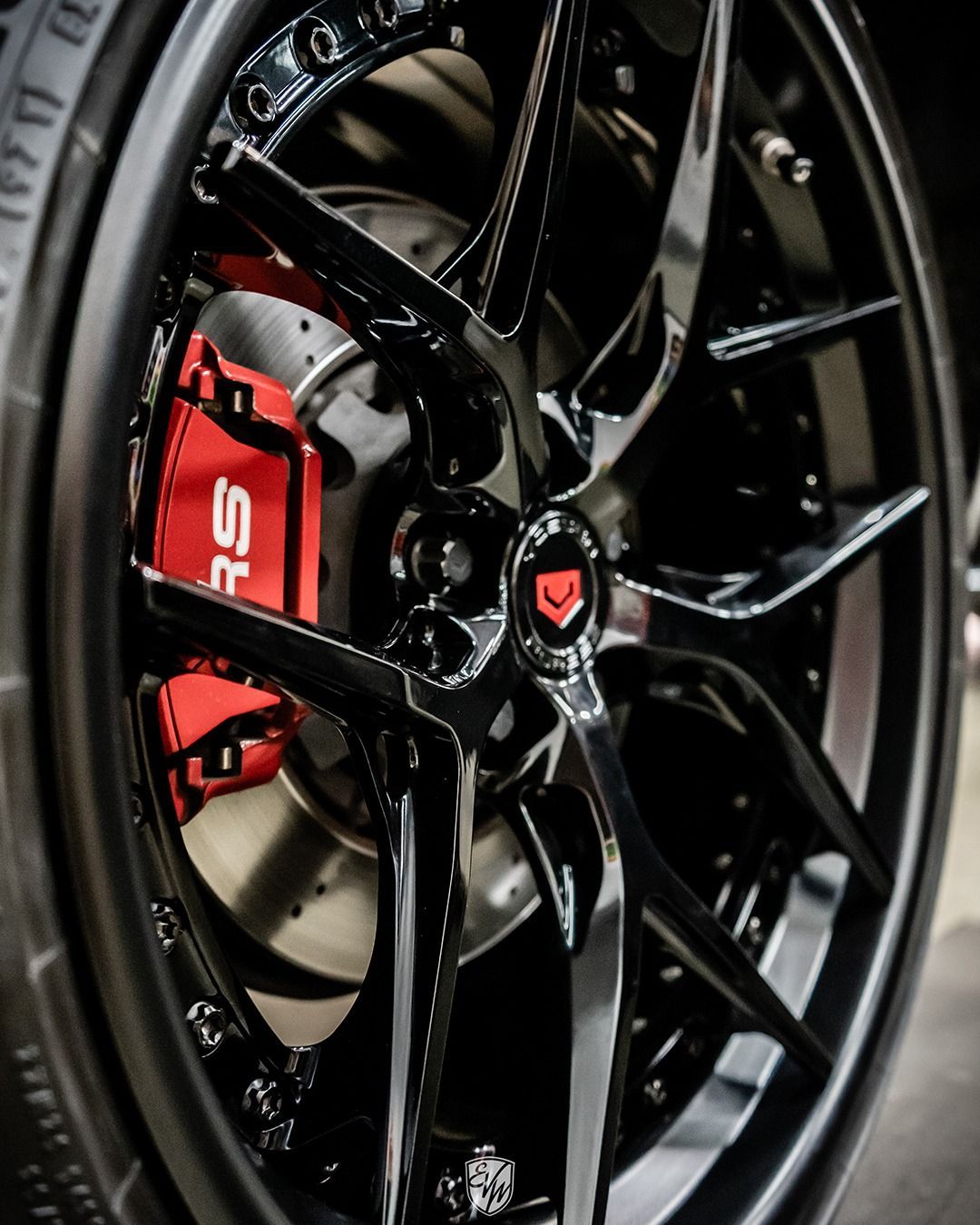 Black car wheel with red brake caliper and