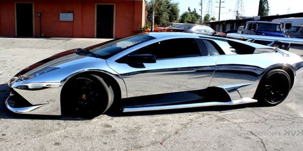 Chrome Lamborghini parked on a gray surface, reflecting the surrounding environment.