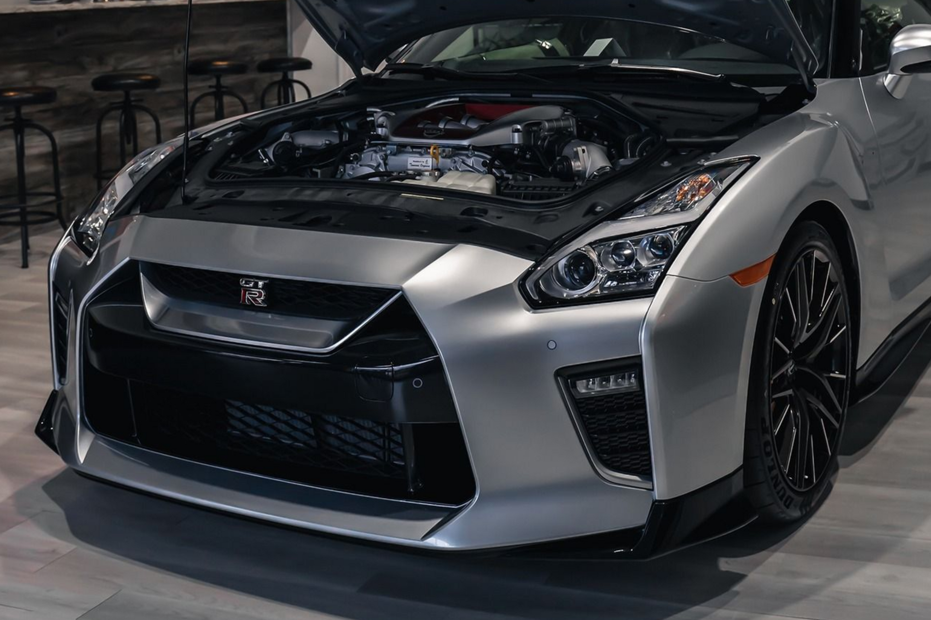 Silver Nissan GT-R sports car with hood open, showing engine.