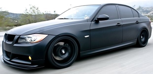 Black BMW sedan with tinted windows and black wheels.