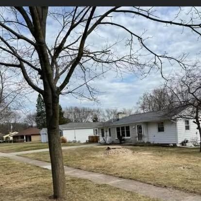 A suburban house with a leafless tree in front; cloudy sky.