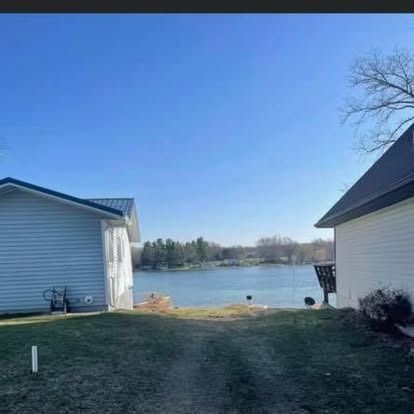 View between two houses of a lake on a sunny day.