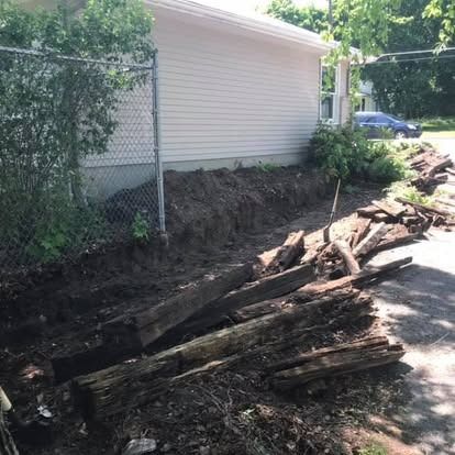 A trench next to a building, with weathered wood and dirt.