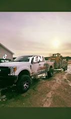 White truck with a trailer hauling equipment.