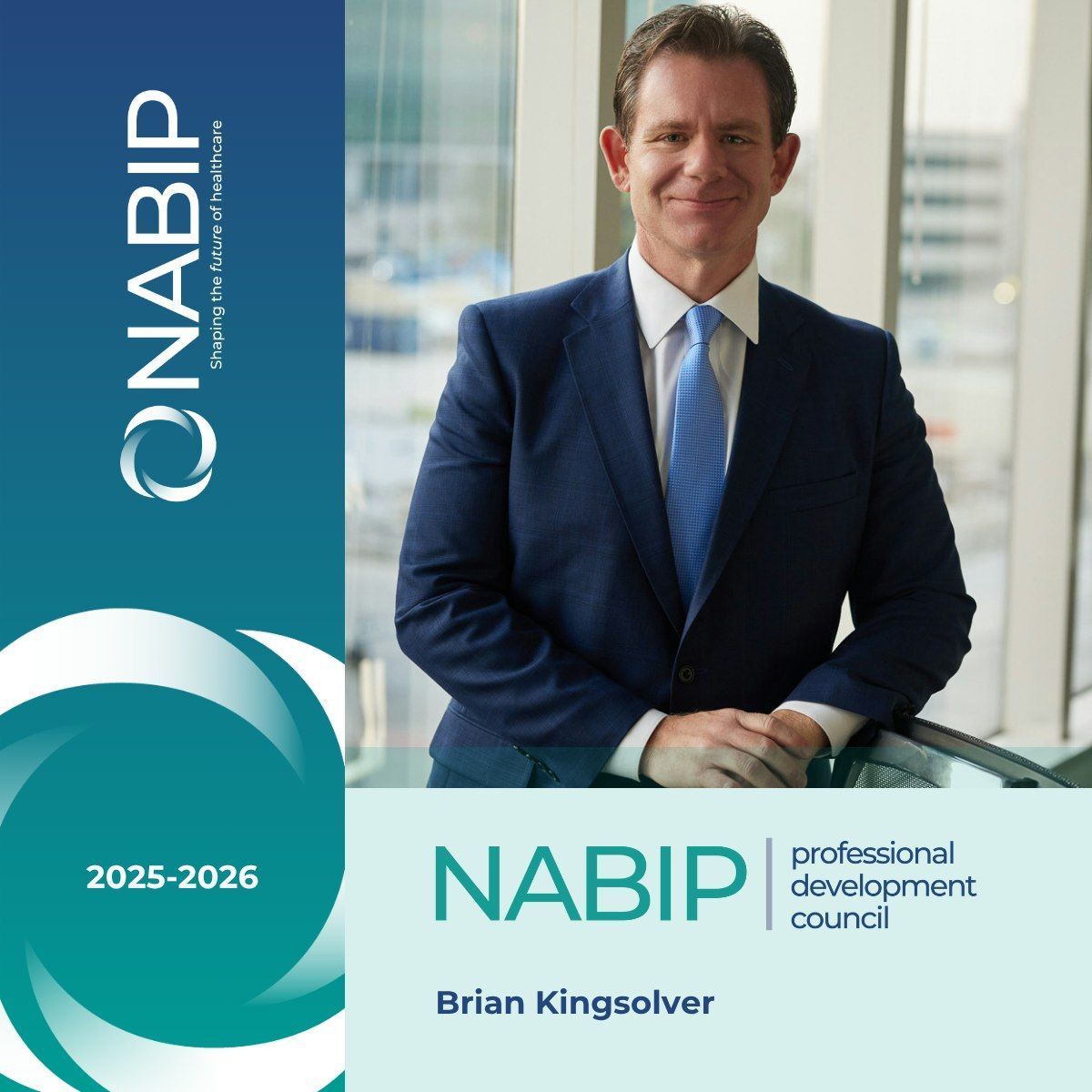 Brian Kingsolver in a suit smiles beside a window with the NABIP logo and