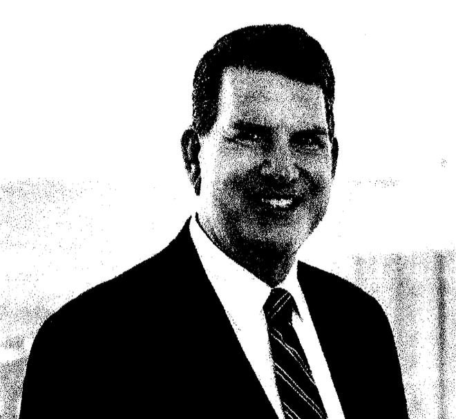 Man in a suit smiles at the camera, white background.