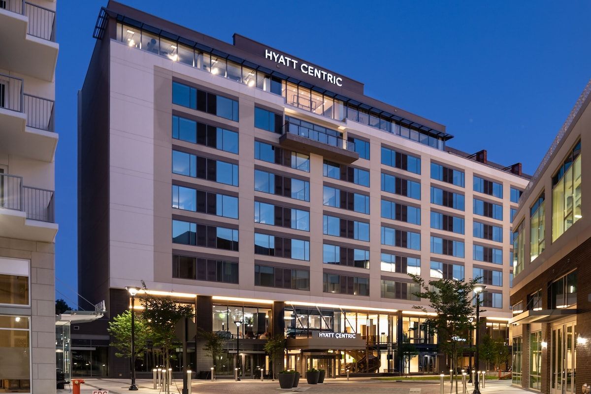 Hyatt Centric hotel exterior at dusk, modern architecture, glass windows, illuminated lobby.