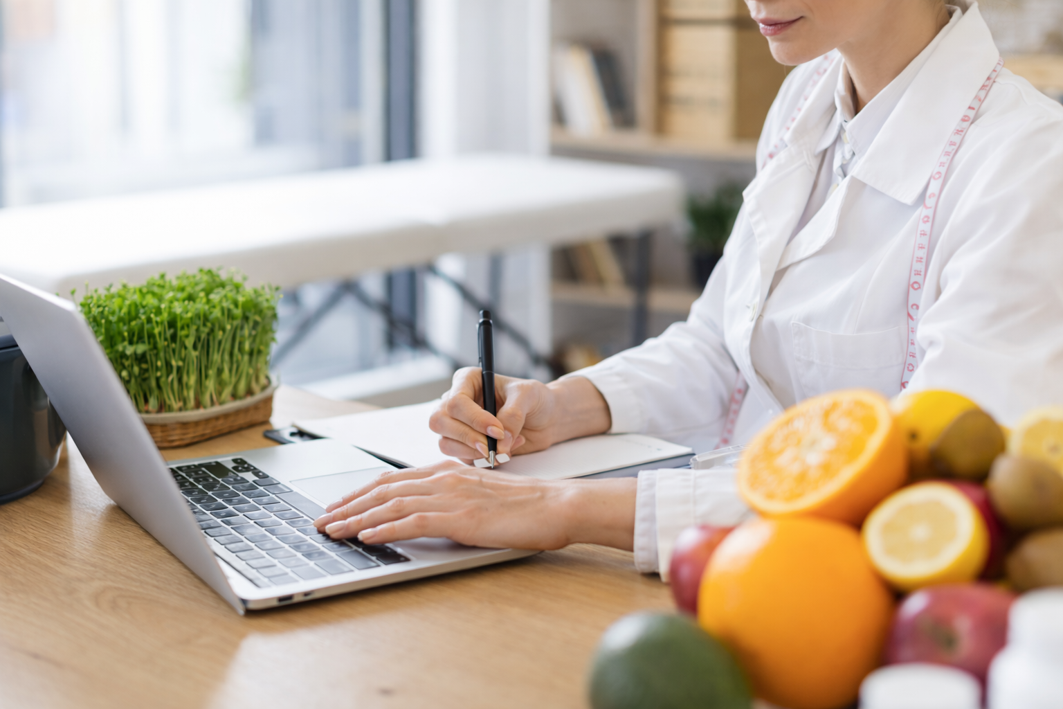 Registered dietitian taking notes at a desk surrounded by fresh fruits and vegetables during a nutrition counseling session at Palestra Spa & Studio in SouthPark, Charlotte.