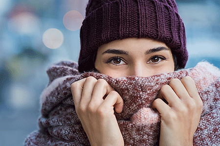 Woman covering her face to protect skin from the cold.