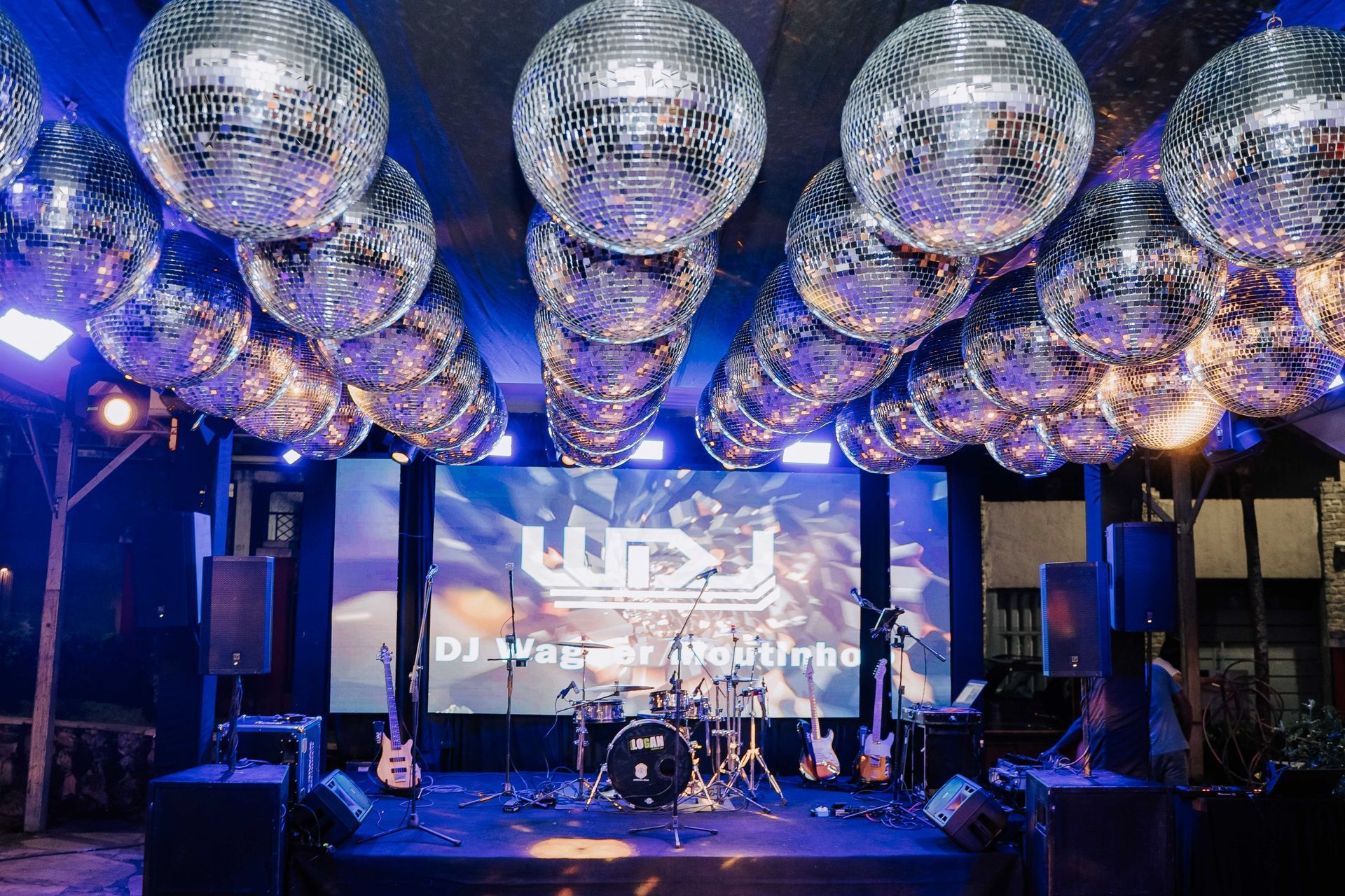 Um palco com uma tela grande e bolas de discoteca penduradas no teto. Hotel Quadrado