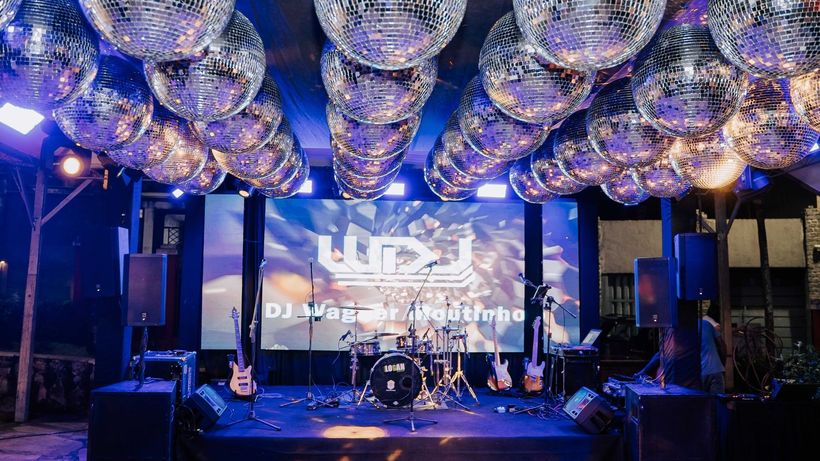 Um palco com uma tela grande e bolas de discoteca penduradas no teto. Hotel Quadrado
