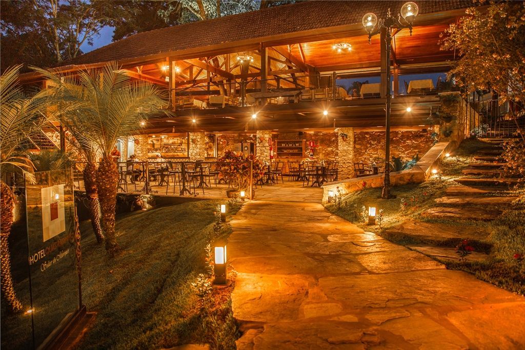 Um restaurante é iluminado à noite e tem uma passarela de pedra que leva até ele. Hotel Quadrado
