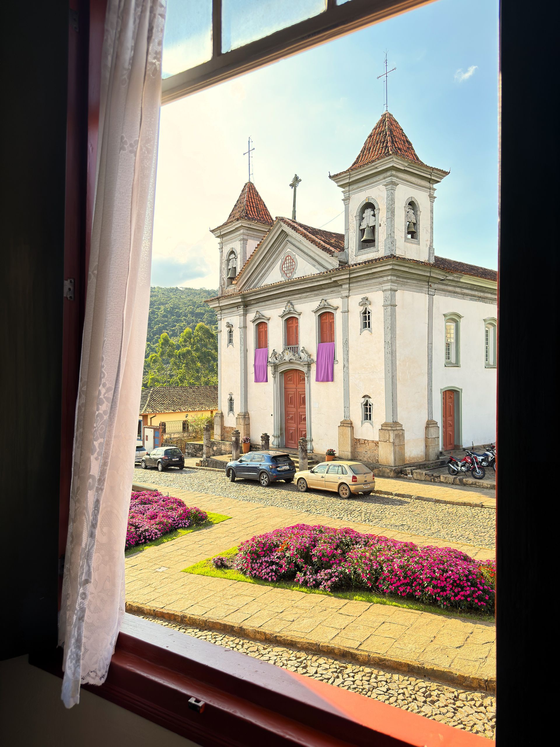 Uma vista de uma igreja de uma janela com flores na frente dela. Hotel Quadrado