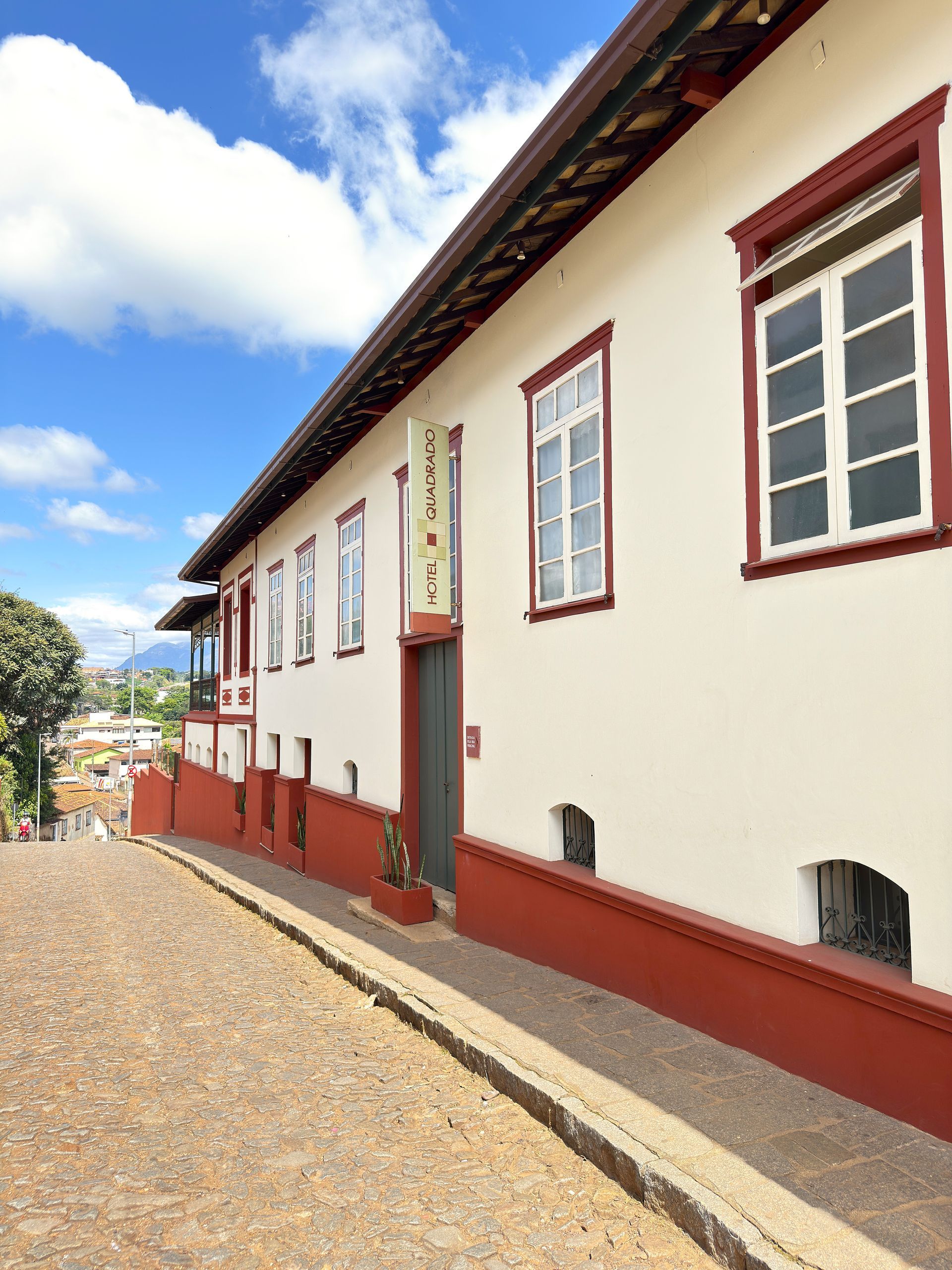 Um grande edifício branco com detalhes e janelas vermelhas. Hotel Quadrado