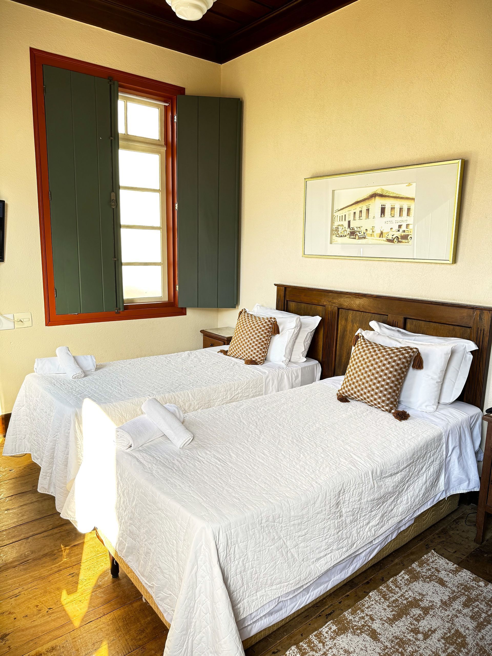 Um quarto com duas camas, uma janela e um quadro na parede. Hotel Quadrado