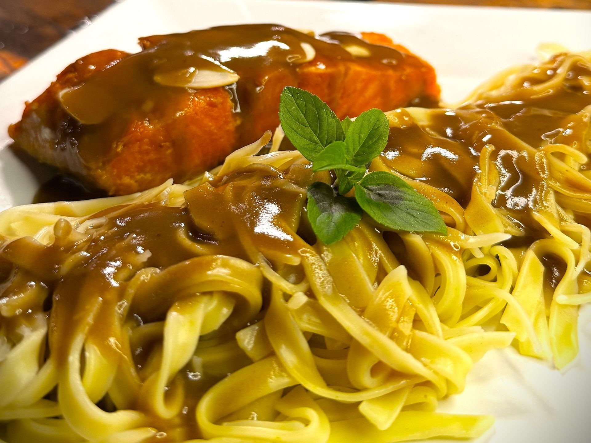 Um prato de macarrão com molho e um pedaço de carne. Hotel Quadrado