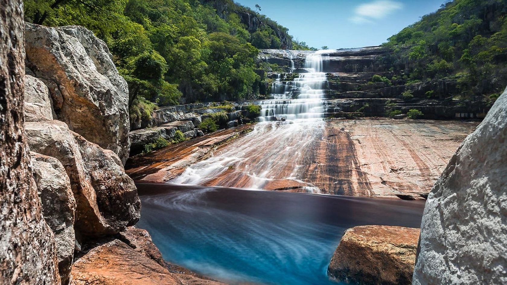 Uma cachoeira é cercada por pedras e árvores no meio de uma floresta. Hotel Quadrado