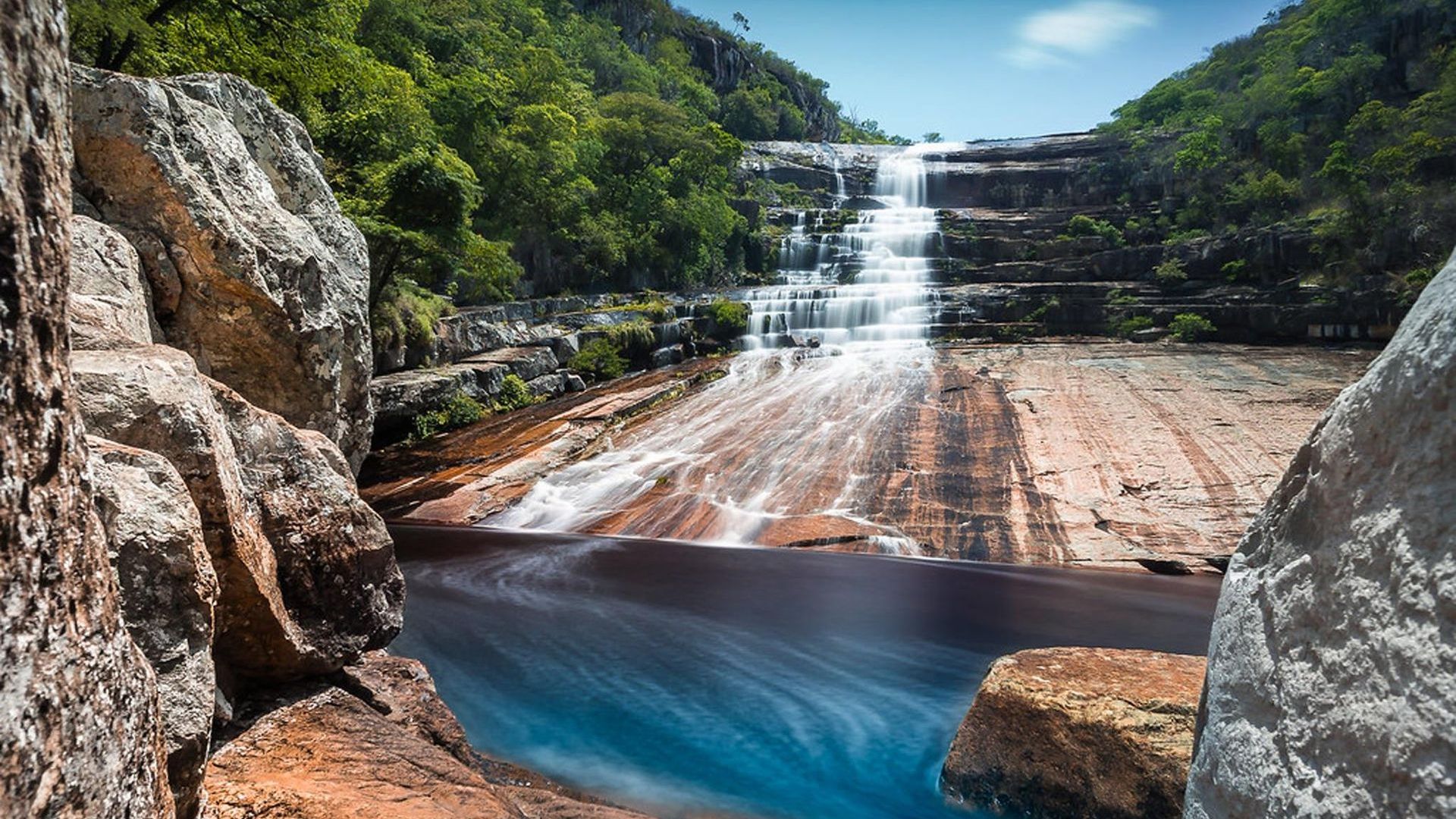 Uma cachoeira é cercada por pedras e árvores no meio de uma floresta. Hotel Quadrado
