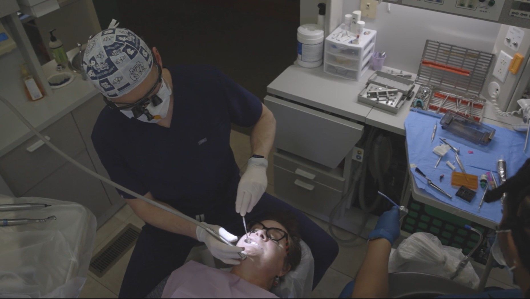 A dentist is examining a patient 's teeth in a dental office.