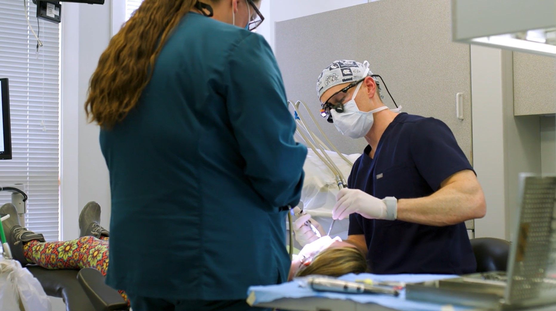 A dentist is examining a patient 's teeth in a dental office.