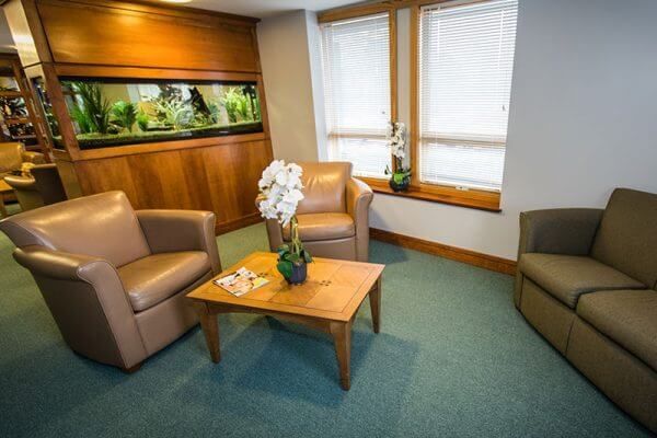 A living room with two chairs , a couch , a table and an aquarium.