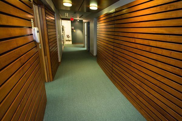 A long hallway with wooden walls and green carpet