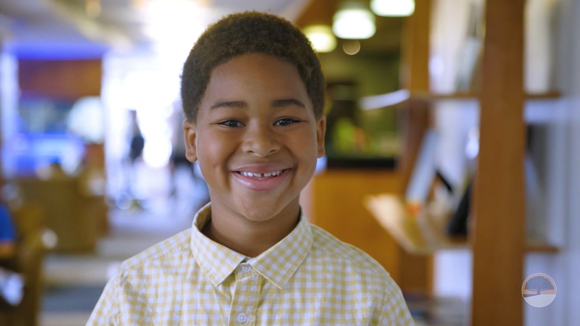 A young boy in a yellow plaid shirt is smiling for the camera.