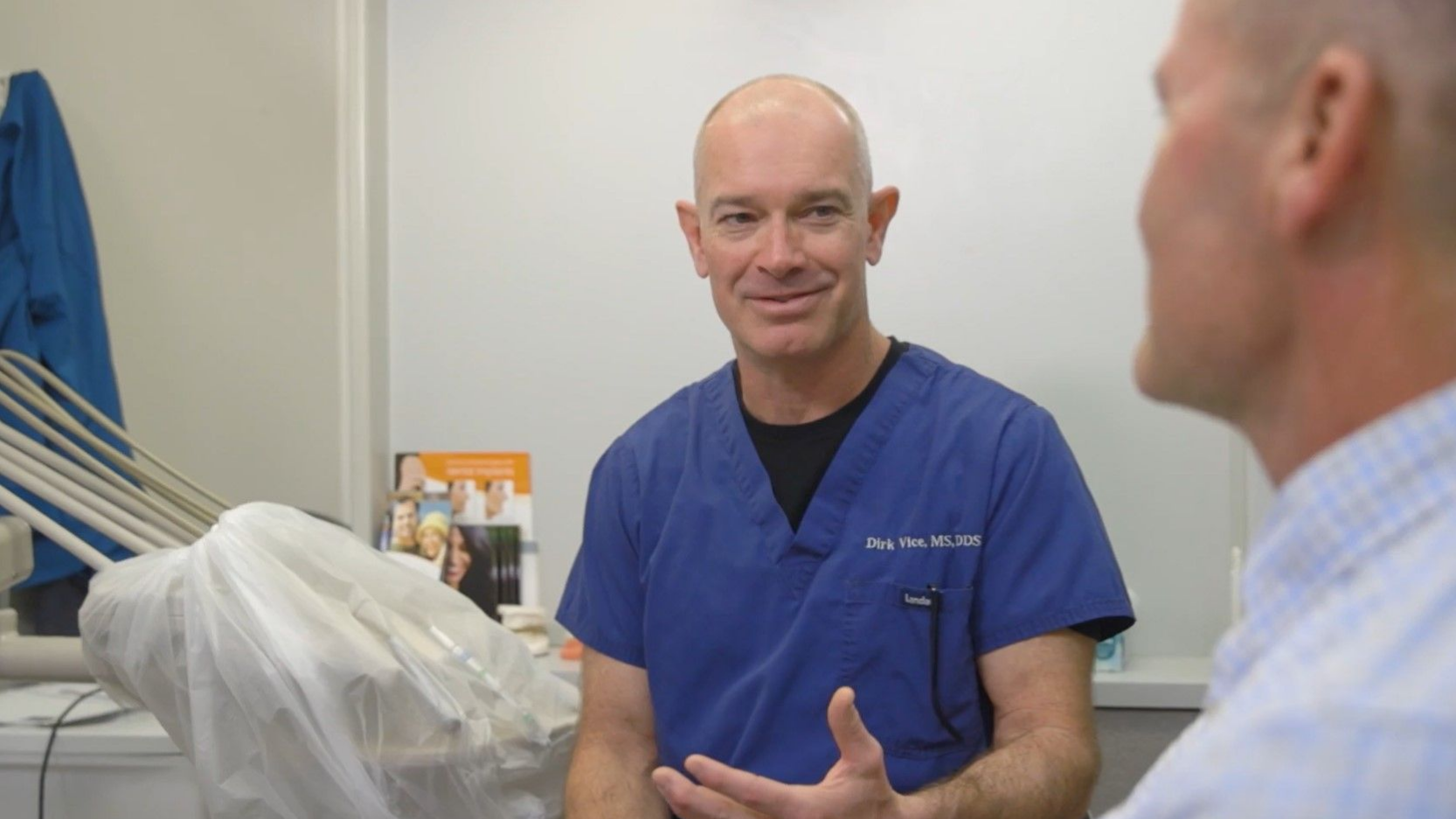 A dentist is talking to a patient in a dental office.
