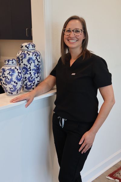 A woman in a black scrub top is standing next to a counter.