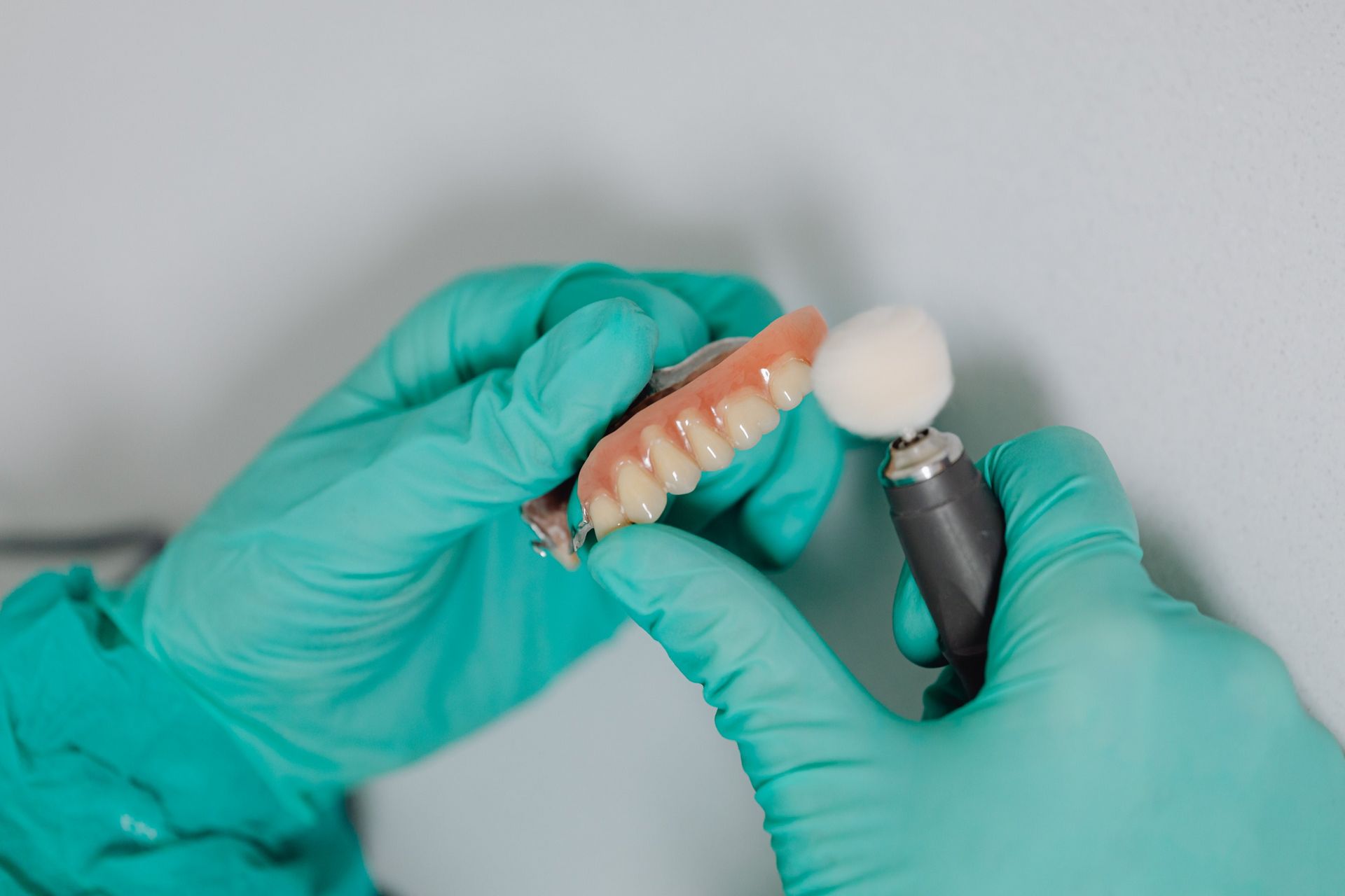 A dentist is polishing a denture with a brush.